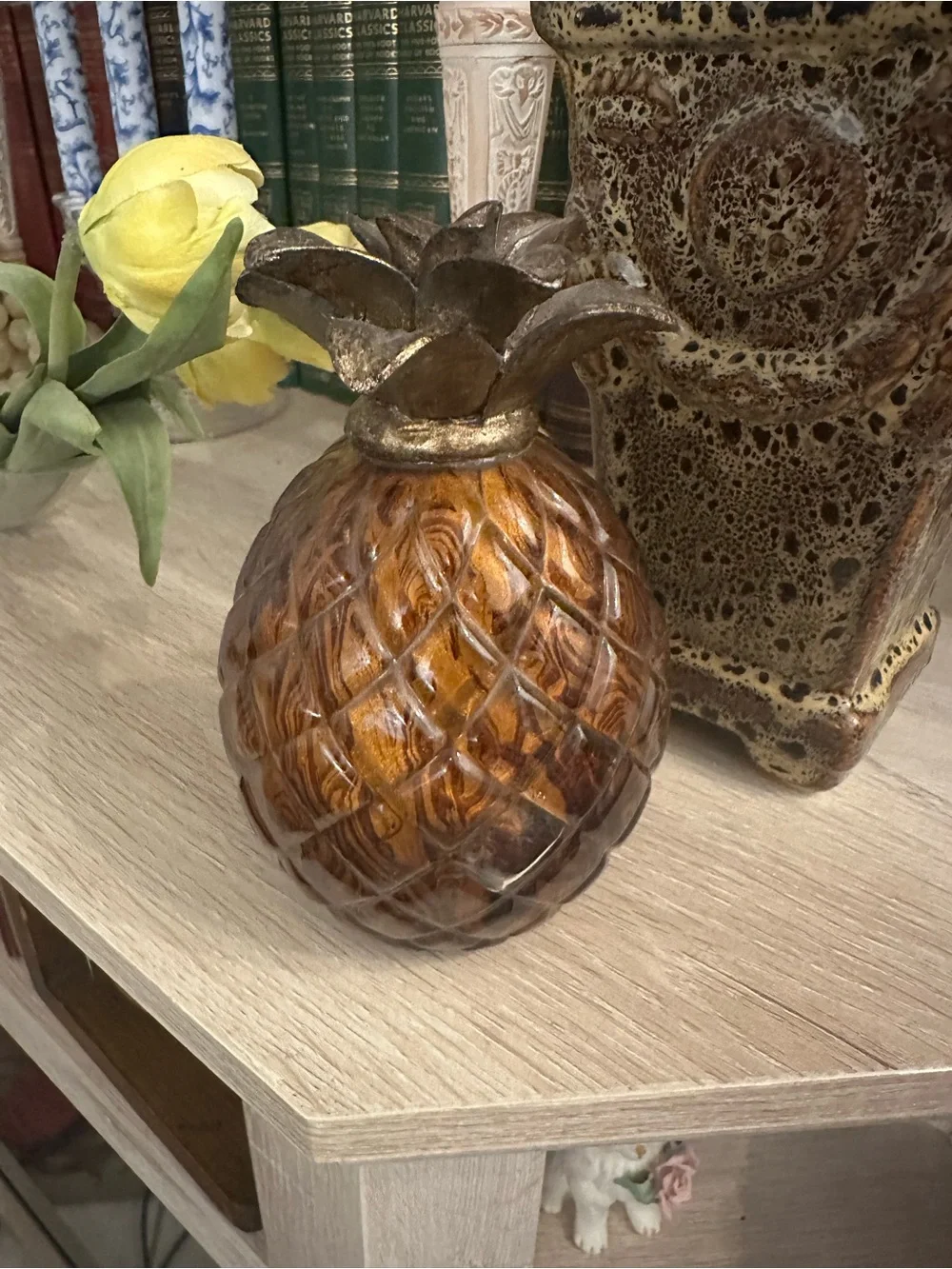 A decorative amber glass pineapple with a metallic leaf top.
